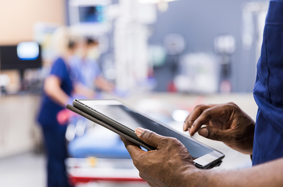 A medical professional working on a tablet in a blue outfit