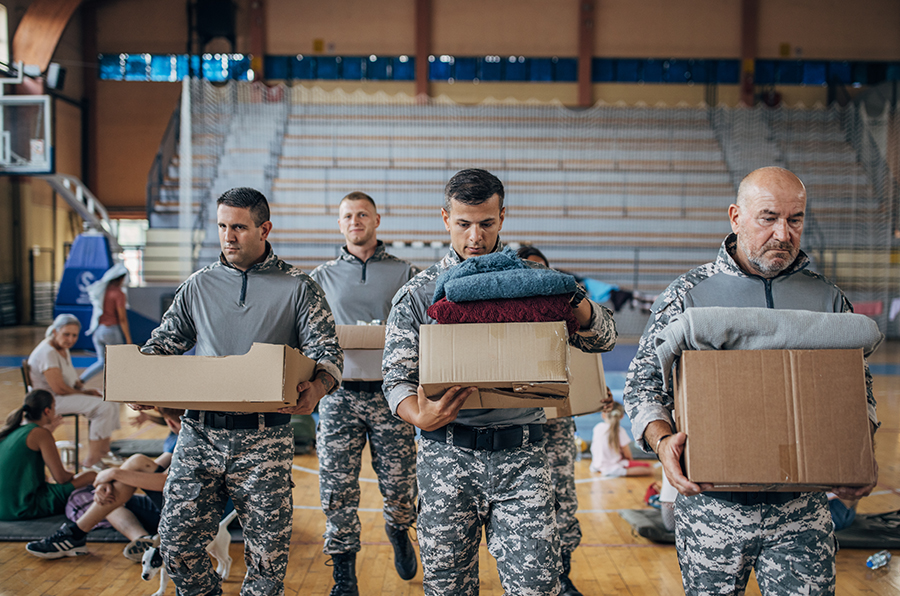 4 men in army uniform helping the community at a high school basketball court