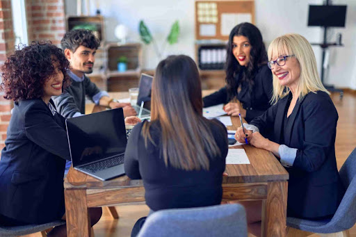 Five members of a private membership association sitting at a desk, discussing collaboration opportunities.